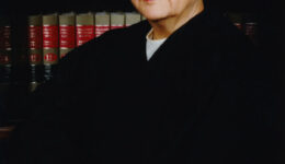Justice Abrahamson wearing her judicial robes, standing in front of shelves full of law books.